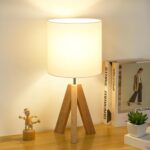 Wooden tripod table lamp with fabric shade.